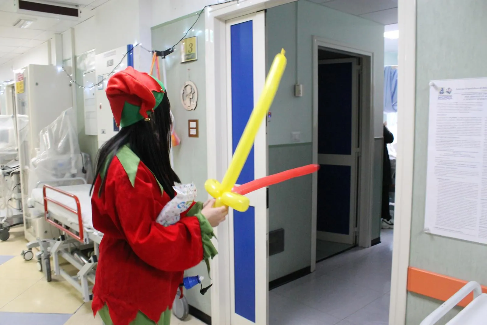 Una volontaria vestita da elfo porta un palloncino in corsia